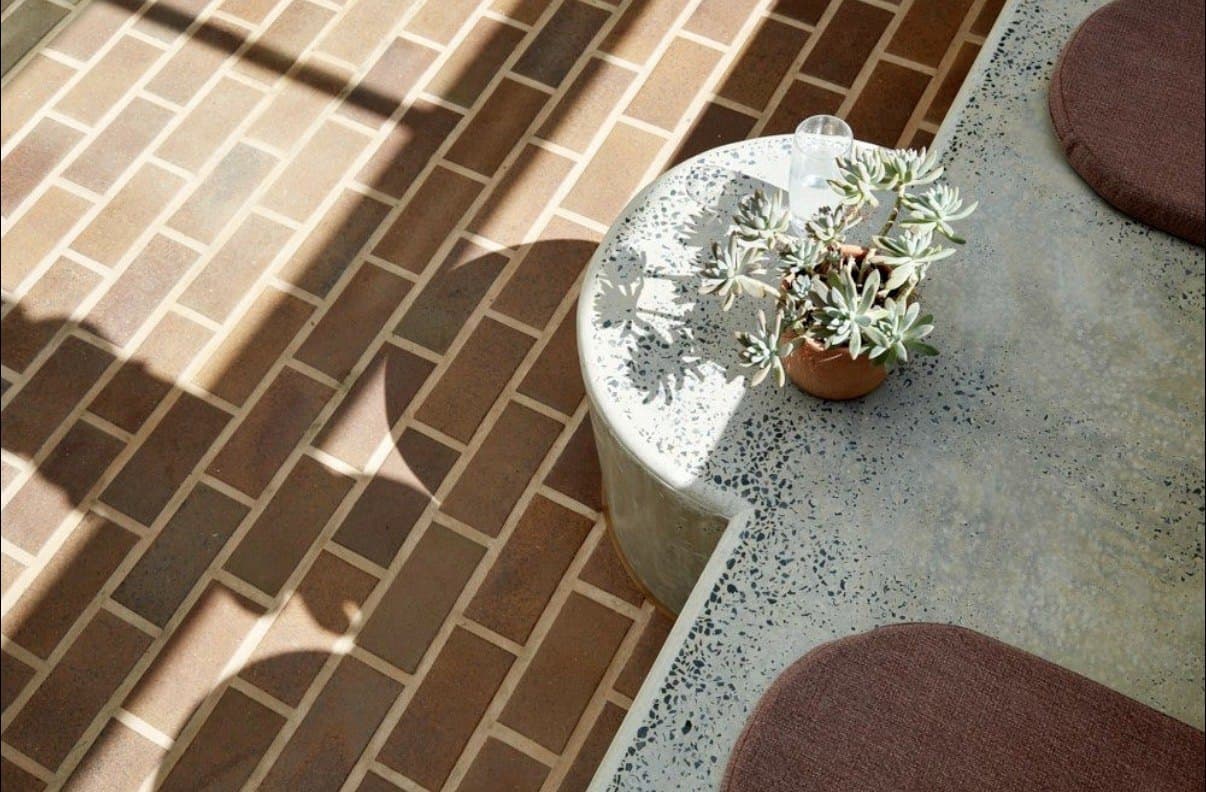 Honed concrete surface showing exposed aggregate next to brick paving