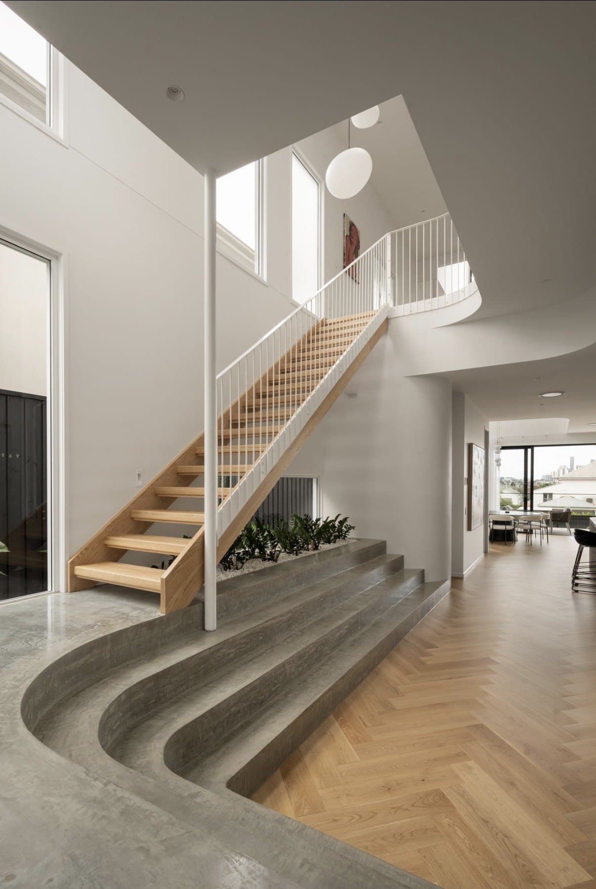 Curved concrete steps beside a timber stair and herringbone floor