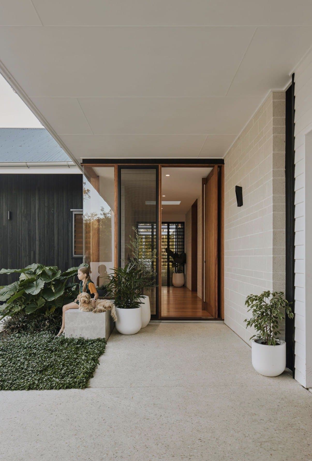 Honed concrete entry path with fine exposed aggregate leading to a timber door