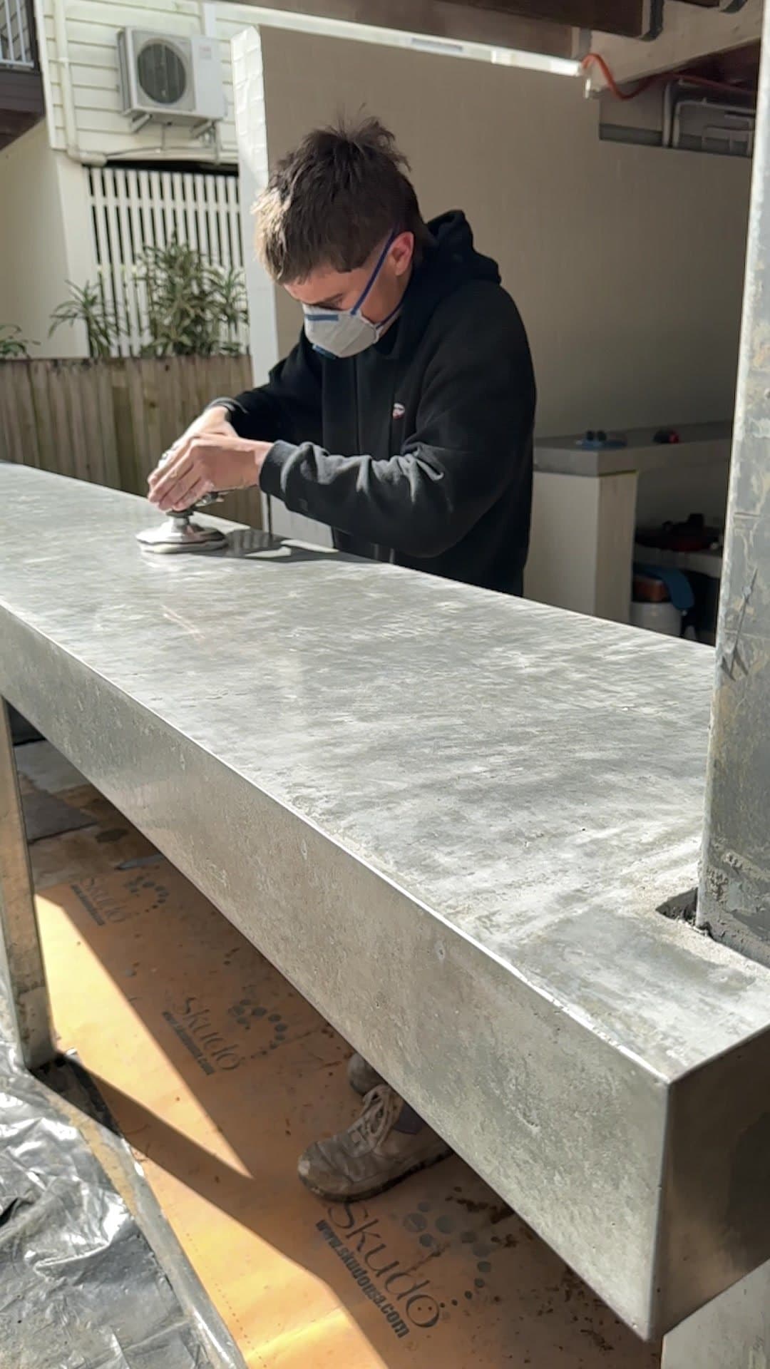 Polishing a long concrete bench by hand in a covered outdoor area