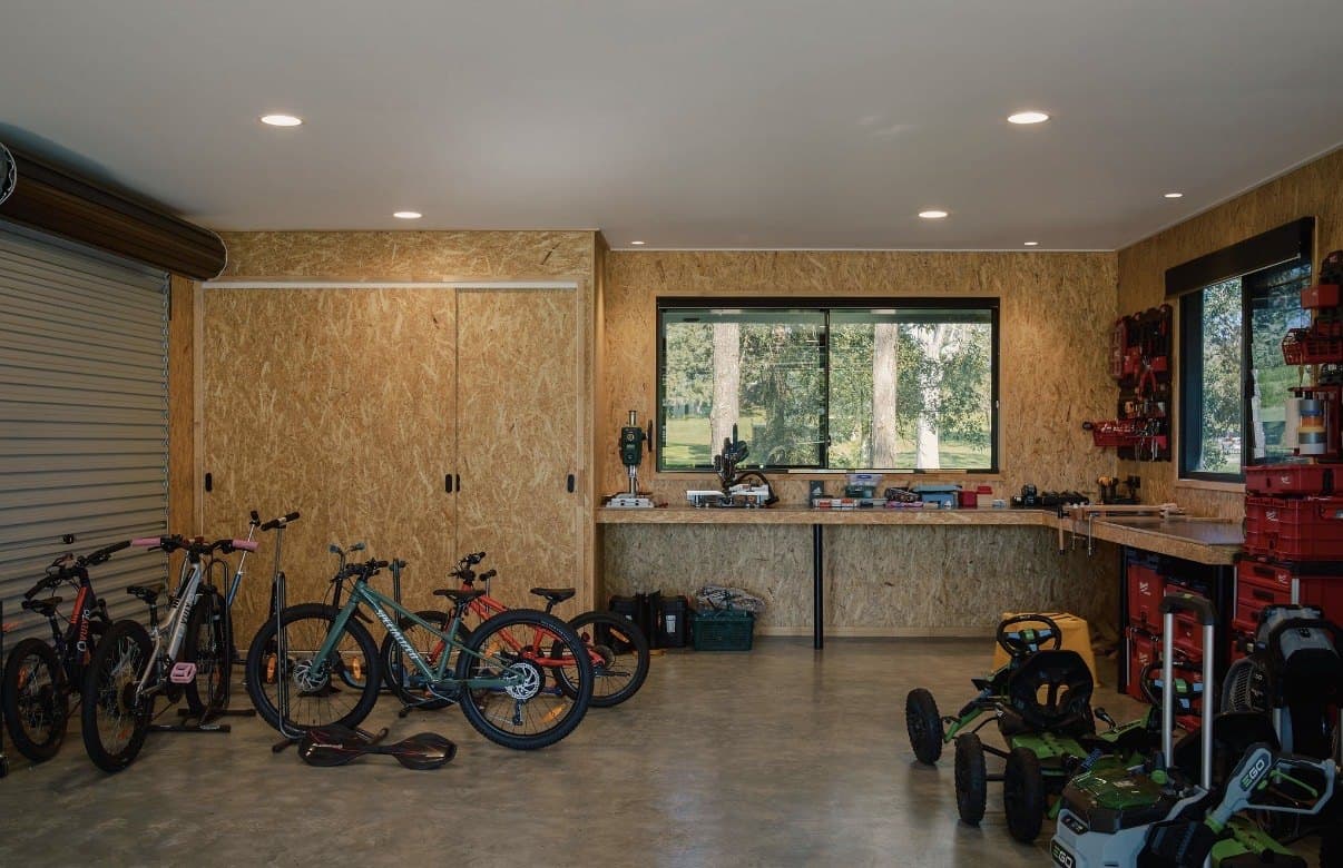 Garage with a ground and sealed concrete floor, bikes and a workbench along the wall