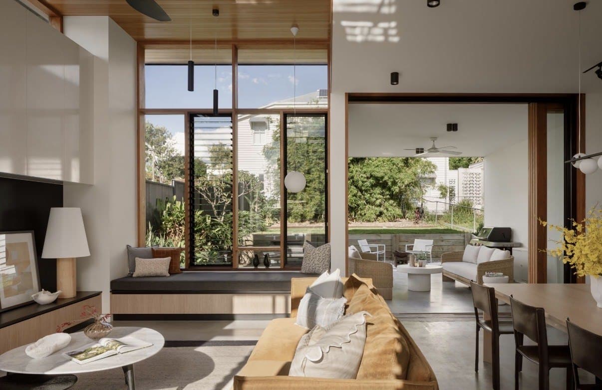 Open-plan living room with a concrete floor and afternoon light from tall windows