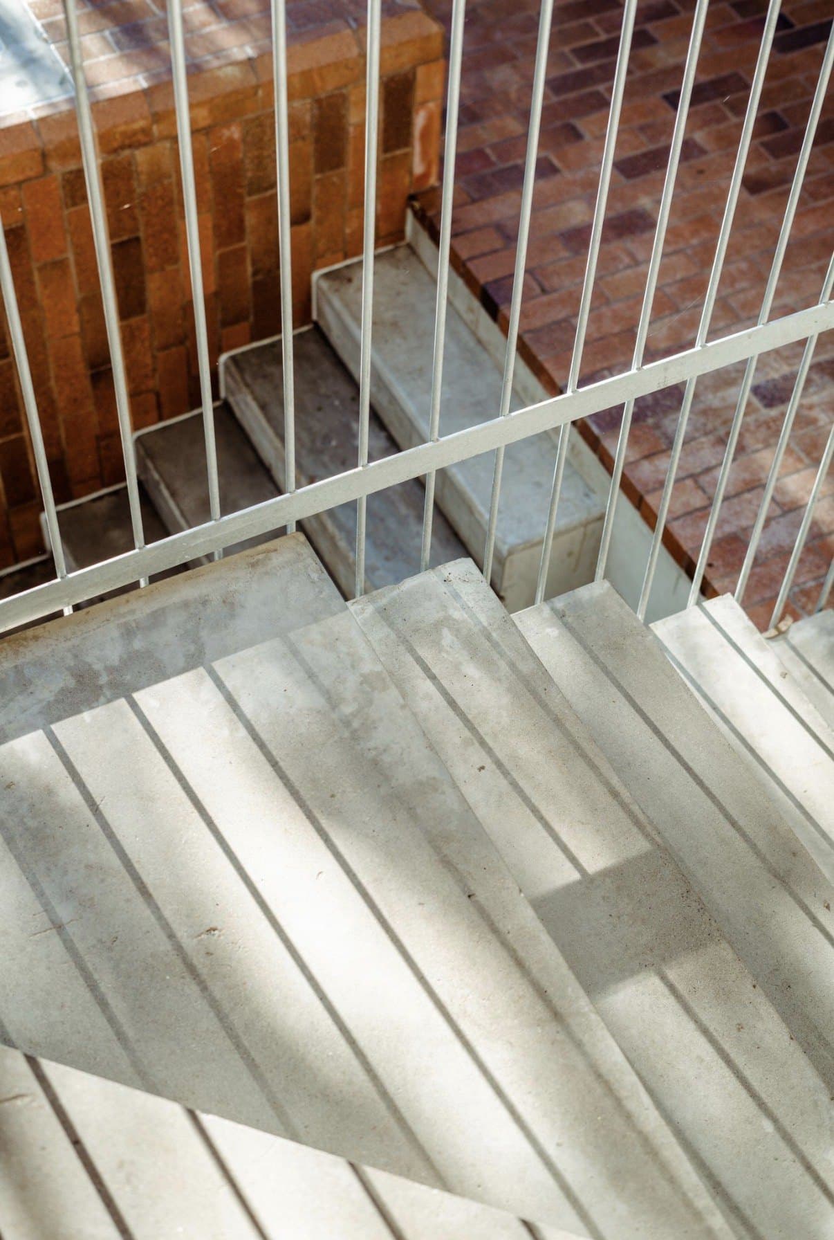 Concrete stair landing with raking light and shadows from a steel balustrade